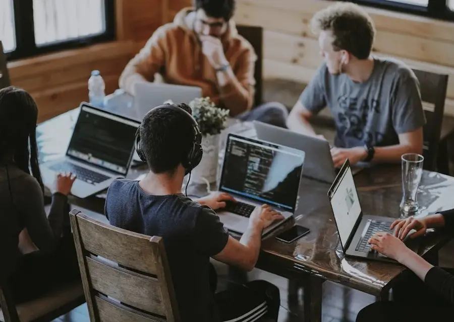 A team collaborating on laptops around a shared workspace table