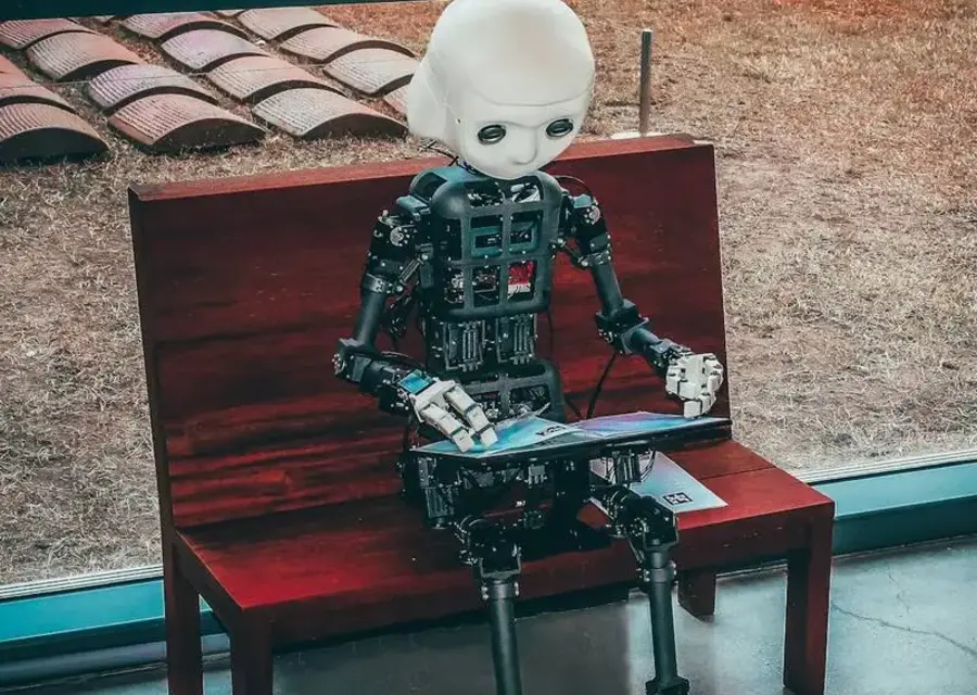 A humanoid robot reading from a tablet, illustrating IT automation that removes repetitive manual work